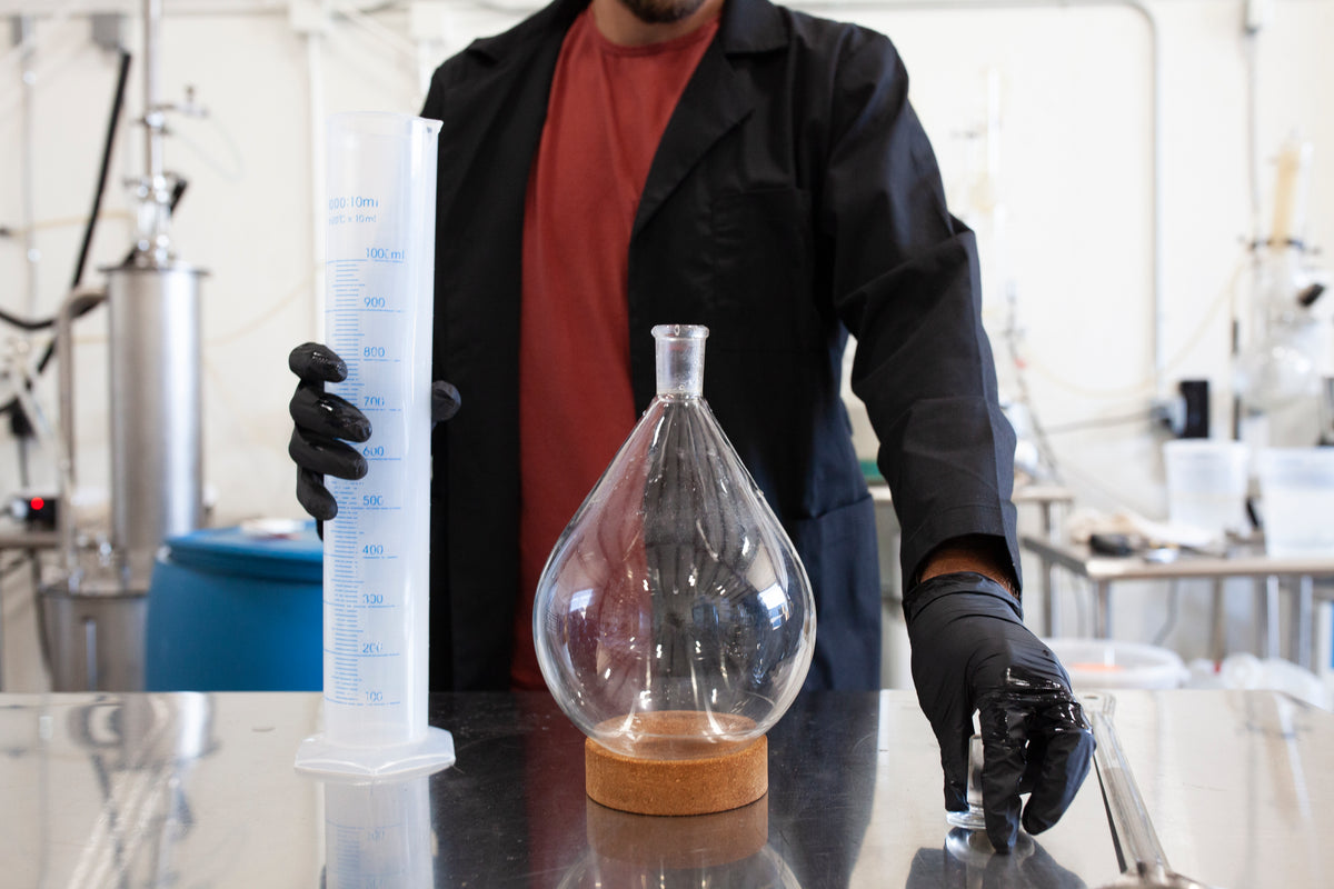 Mushroom extract in a glass flask beside a graduated cylinder