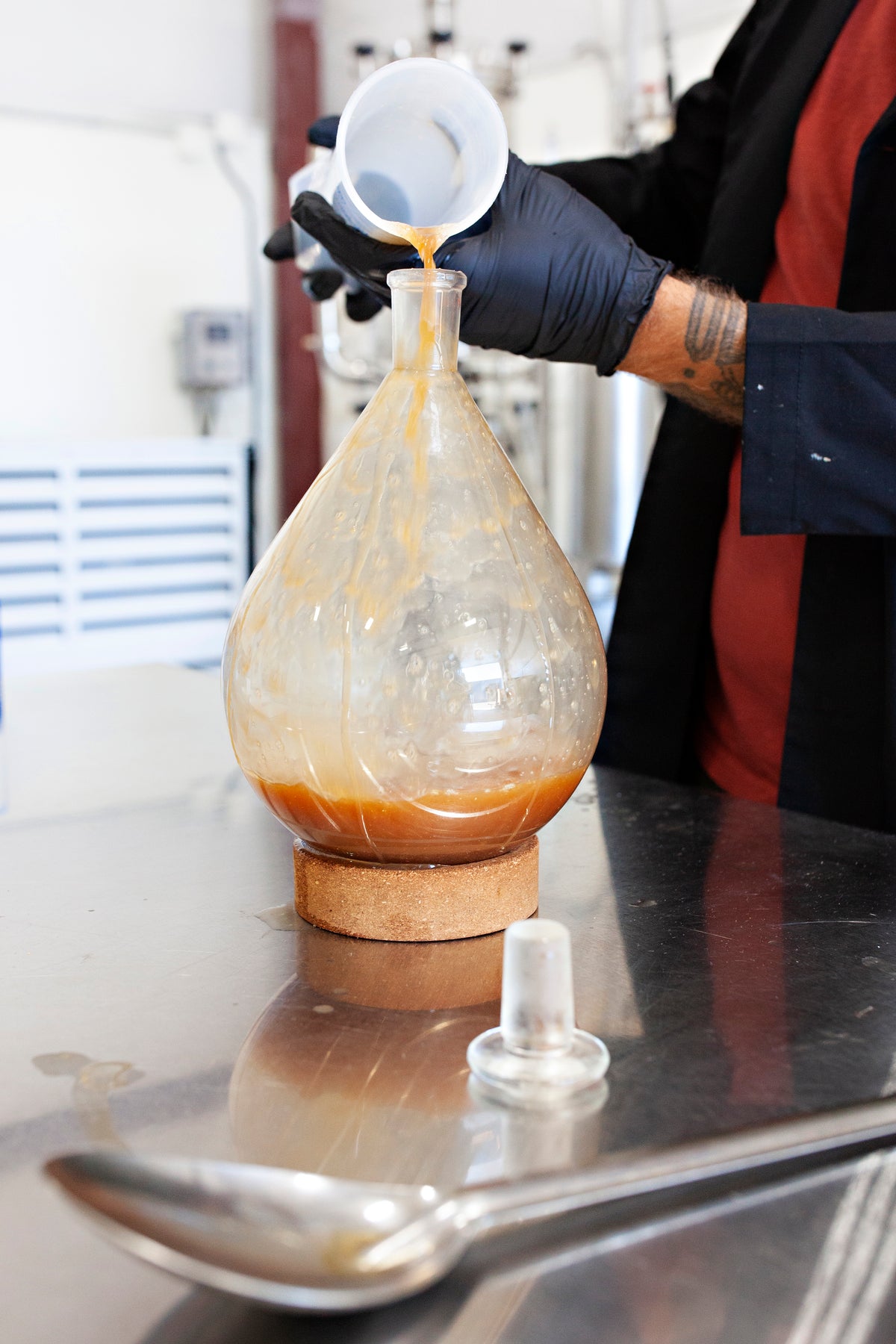 Pouring mushroom extract into a round glass flask in the Feral Fungi lab