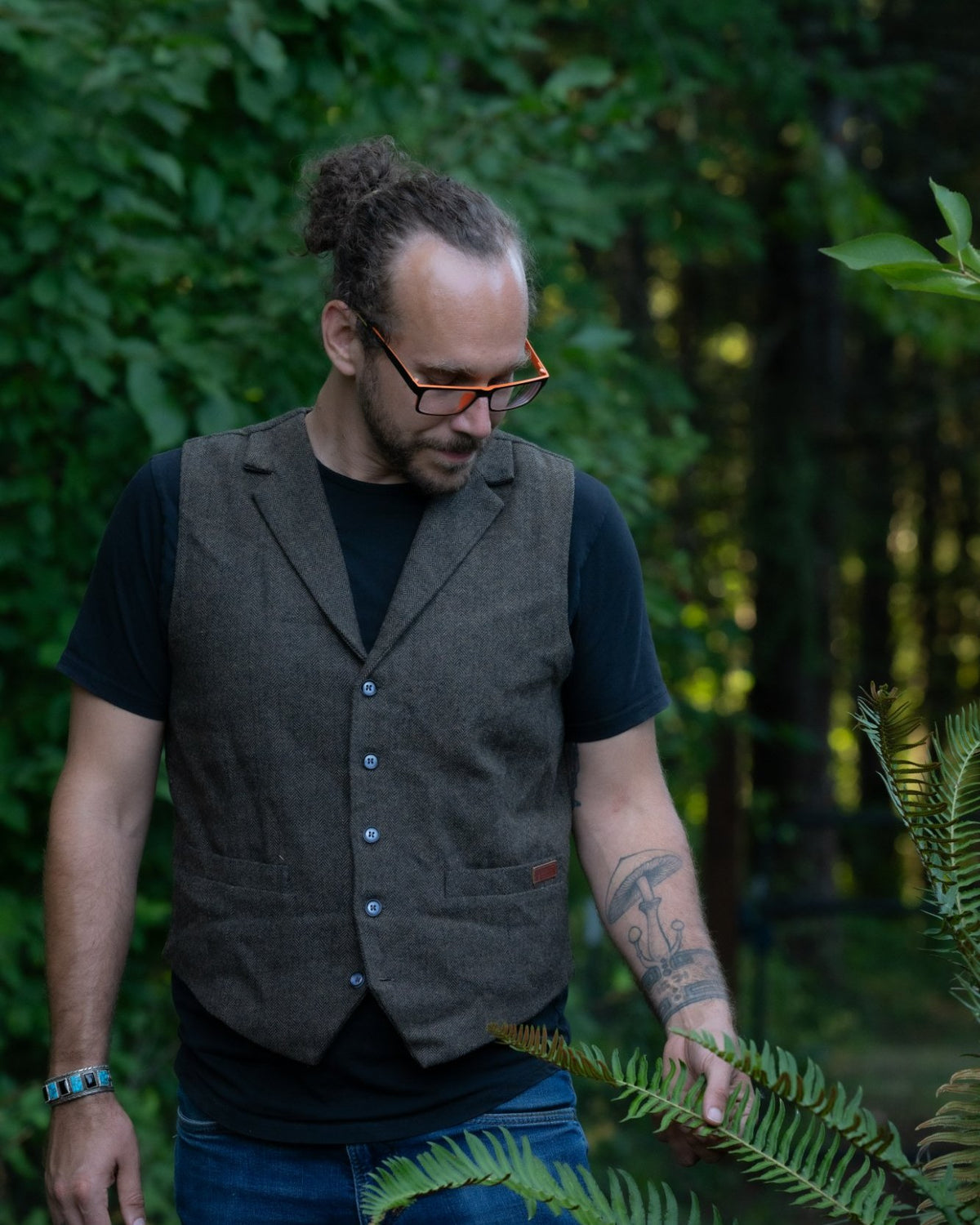 Jason Scott in the forest, looking down at a sword fern